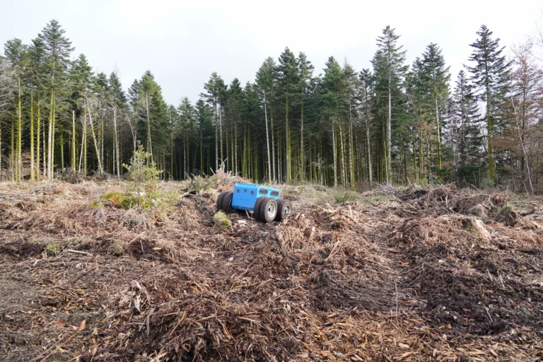 Le robot Quator de Sfynx Industry évolue sur un terrain forestier recouvert de feuilles et de branches. Grâce à sa configuration à double roue motrice et sa conception robuste, ce robot tout-terrain assure une excellente stabilité et une adhérence optimale dans les environnements naturels complexes.